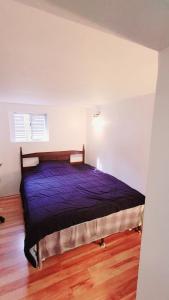 a bedroom with a bed with a purple comforter at Vancouver 2BR Garden Suite in Vancouver