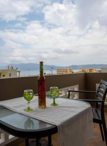 uma mesa com dois copos de vinho e uma garrafa em Πράσινη πινελιά διαμέρισμα em Kissamos