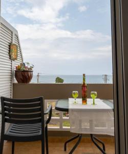 un tavolo e una sedia su un balcone con tavolo e bicchieri da vino di Πράσινη πινελιά διαμέρισμα a Kíssamos