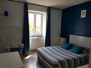 een slaapkamer met een bed met blauwe muren en een raam bij Les forges de Planechaud in Saint-Sornin-Leulac