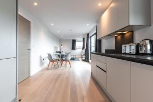 a kitchen with white cabinets and a table with chairs at Apartment Forty Staines Upon Thames - Free Parking - Heathrow - Thorpe Park in Staines