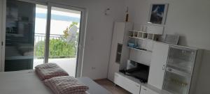sala de estar con cama, TV y ventana en Apartments Sonne, en Crikvenica