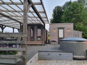 a tiny house sitting on top of a wooden deck at Purenes - Barrel shaped pod with hot tube in Sliseri