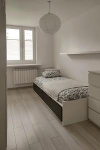 um quarto branco com uma cama e 2 janelas em Warszawa Mieszkanie 4 em Varsóvia
