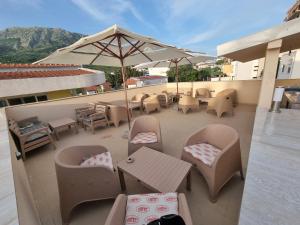 a patio with tables and chairs and an umbrella at Ebra Lux Apartmani in Dobra Voda