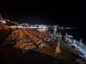 a row of lounge chairs and umbrellas on a beach at night at Ebra Lux Apartmani in Dobra Voda