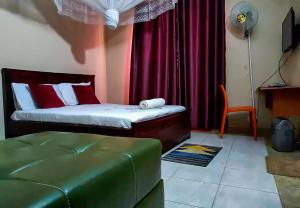 a bedroom with a bed with red curtains and a chair at Conbary Hotel in Wakiso