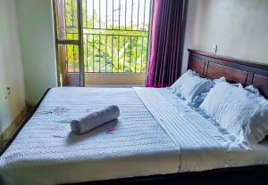 a large bed with a pillow on it with a window at Conbary Hotel in Wakiso