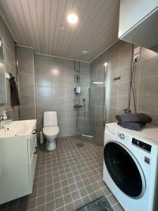 a bathroom with a washing machine and a toilet at Casa Opaali in Tampere