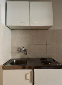 uma cozinha com um lavatório e armários brancos em Old Town Apartment em Herceg Novi
