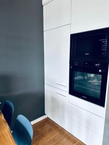 a kitchen with white cabinets and a microwave at Bovis APARTMENT - Gdynia Center Rezydencja Redłowo in Gdynia