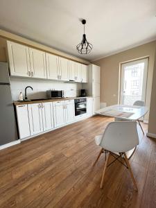 a kitchen with white cabinets and a table and a chair at Apartament Cluj in Cluj-Napoca