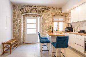 - une cuisine avec des placards blancs et des chaises bleues dans l'établissement Apartmani Boras, à Metković