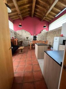 una cocina con una pared rosa y una mesa en El horno Albergue Manzanos, en Manzanos