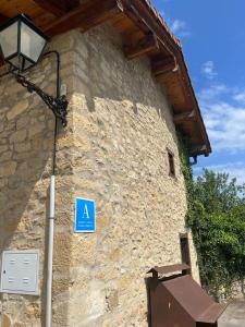 een blauw bord aan de zijkant van een stenen gebouw bij El horno Albergue Manzanos in Manzanos