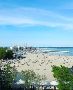 een groep mensen op een strand met een pier bij Bovis APARTMENT - Gdynia Center Rezydencja Redłowo in Gdynia