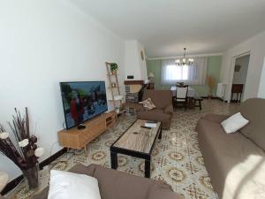 ein Wohnzimmer mit einem Sofa und einem Flachbild-TV in der Unterkunft Villa le Yucca proche des plages catalanes in Bompas