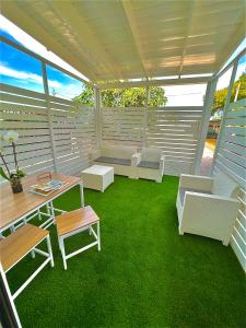 una veranda riparata con mobili bianchi e erba verde di Villa Latino a Vieste