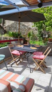una mesa y sillas con una sombrilla en el patio en Gîtes chez Daniel "Cevennes 3", en Mars