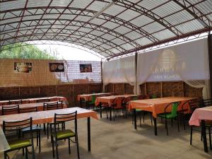 un comedor con mesas, sillas y una pantalla en AltynAi Guest House en Cholpon-Ata