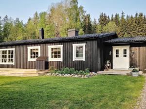 una casa negra con ventanas blancas y un patio en Holiday home Gunnarskog II, en Gunnarskog