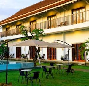 a patio with tables and an umbrella in front of a building at Tantra Hotel in Krui