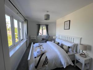 a bedroom with a white bed and a window at Studland View Cottage in Studland
