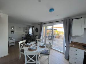 una cucina e una sala da pranzo con tavolo e sedie bianchi di Studland View Cottage a Studland