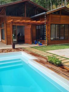 a house with a swimming pool in front of it at Linda Casa de Campo com Piscina na Rota dos Ipês in Domingos Martins