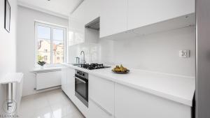 a white kitchen with a stove and a sink at Flatbook - In the Heart of Old Town Apartments Sw Ducha in Gdańsk