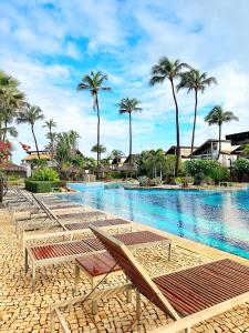 a large swimming pool with chairs and palm trees at Taíba Beach Resort Surf House in Taíba