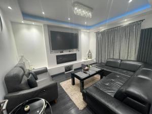 un soggiorno con mobili in pelle nera e TV a schermo piatto di Luxury Holiday Home a Manchester