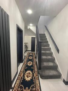 a hallway with stairs and a rug at Luxury Holiday Home in Manchester