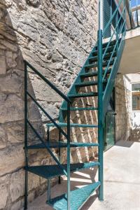 a green metal staircase next to a stone wall at Apartment Silvana in Split
