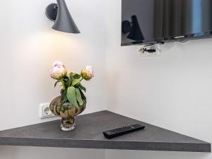 een vaas met bloemen op een plank met een televisie bij Apartment Wendtorf XXVII in Wendtorf