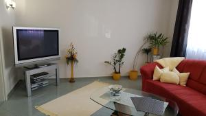 a living room with a red couch and a tv at ALACARD Ferienwohnungen Höffgen Thale Harz in Thale