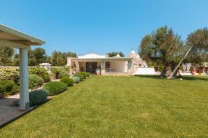 uma casa com um quintal com relva e arbustos em Trulli Olea with Pool em San Vito dei Normanni