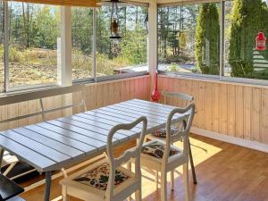 einen Holztisch und Stühle in einem Zimmer mit Fenstern in der Unterkunft Holiday home VÄRMDÖ V in Värmdö