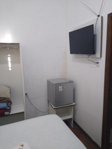 um quarto com uma televisão no canto de uma parede em Central 2 - Pousada em Uruguaiana
