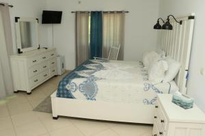 a bedroom with a bed with a dresser and a mirror at Cidade Paradise Guesthouse in Cidade Velha