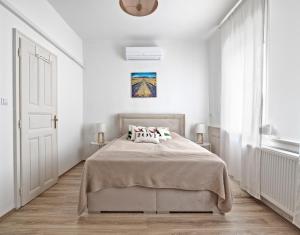 Dormitorio blanco con cama y reloj en la pared en Szent György Kúria, en Kisharsány