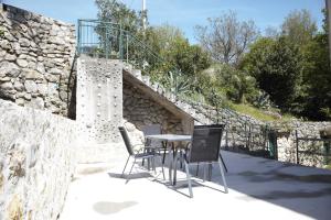 una mesa y sillas en un patio con una pared de piedra en Apartments Sonne 2, en Crikvenica