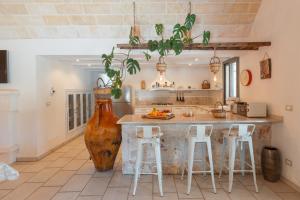 uma cozinha com um vaso grande e um balcão com bancos em Trulli Olea with Pool em San Vito dei Normanni