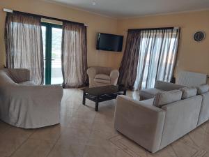 a living room with two couches and a tv at MARMARI Village in Ayía Marína