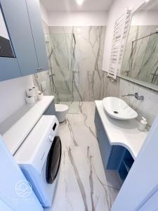 a white bathroom with a sink and a toilet at Apartamenty Bałtyckie - Luxoro Park in Ustka