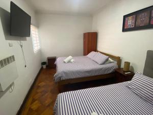 a room with two beds and a flat screen tv at Atacama Hostel Backpackers in Santiago