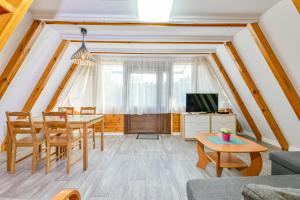 a living room with a table and chairs and a tv at Domki letniskowe Zakątek Kołobrzeg in Kołobrzeg