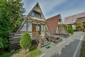 a house with a group of chairs in front of it at Domki letniskowe Zakątek Kołobrzeg in Kołobrzeg