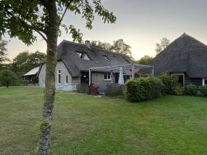 una casa con techo de paja y patio en De Boerderij - Buitenplaats Ruitenveen, privé, en Nieuwleusen