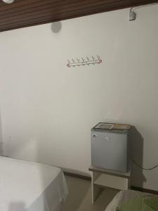 Dieses weiße Zimmer verfügt über ein Bett und einen TV an der Wand. in der Unterkunft Central 2 - Pousada in Uruguaiana